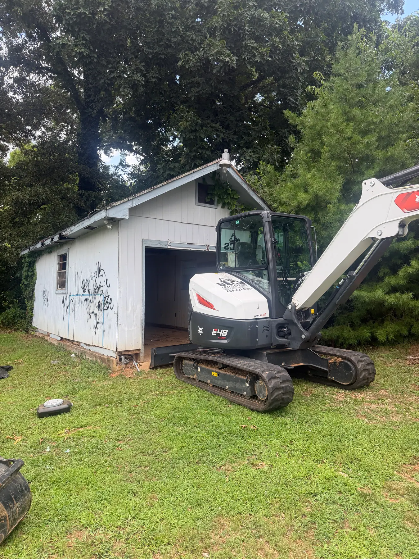 BECS excavator beside a small outbuilding during a removal project