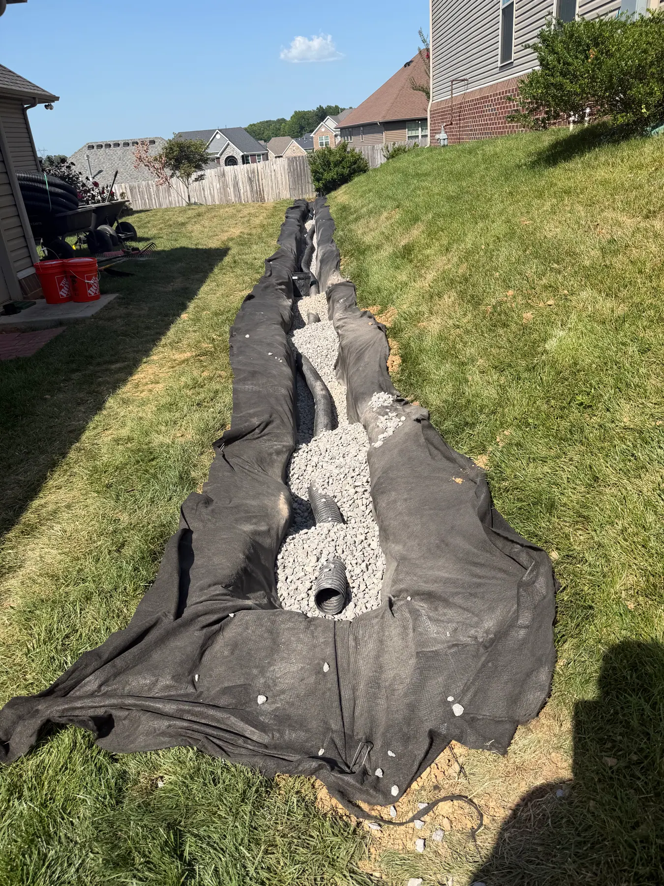 Drainage pipe, stone and fabric laid in a trench between residential yards