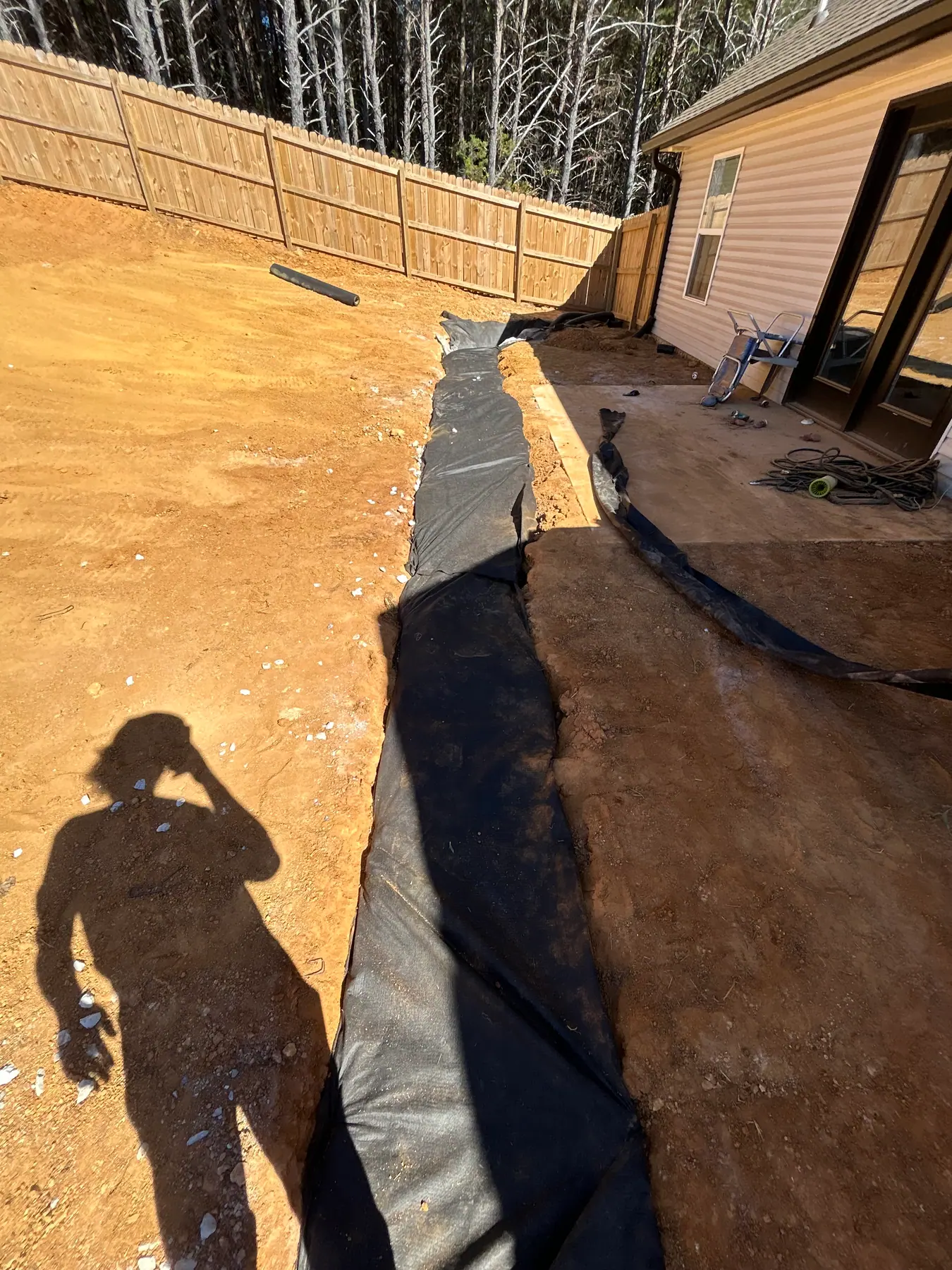 Fabric-lined drainage trench along the side of a house