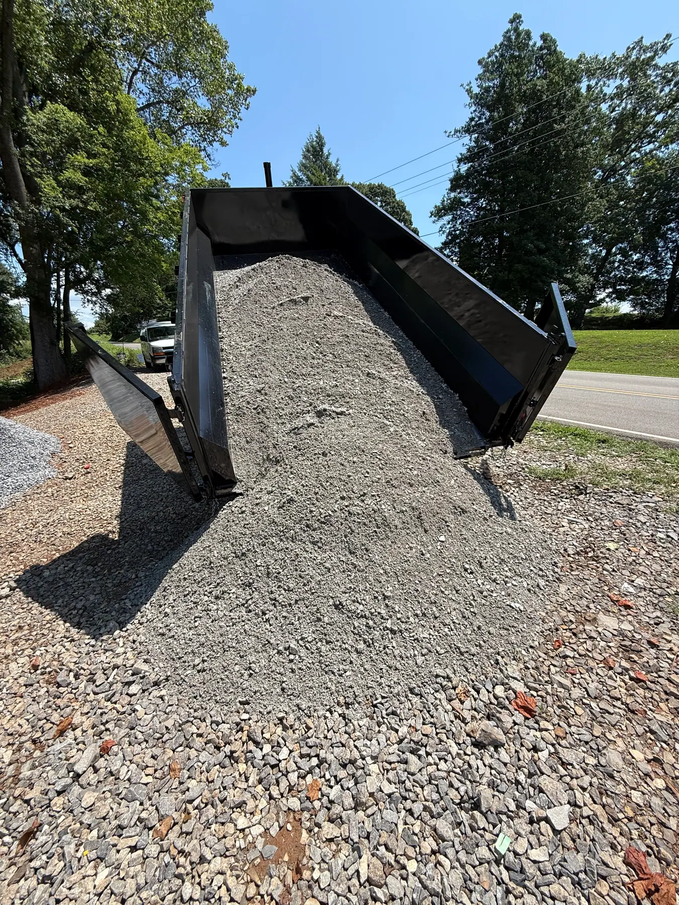 Gravel being unloaded from a dump trailer onto a driveway