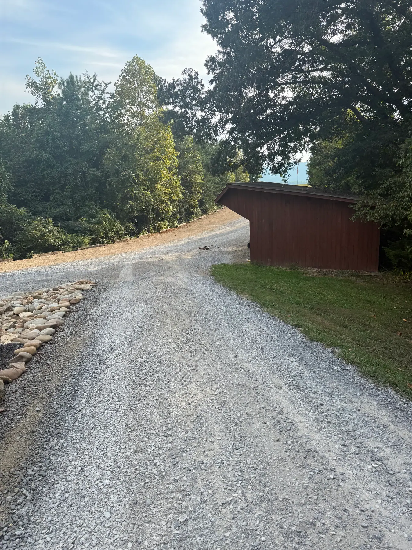 Gravel driveway beside a red outbuilding and stone edging