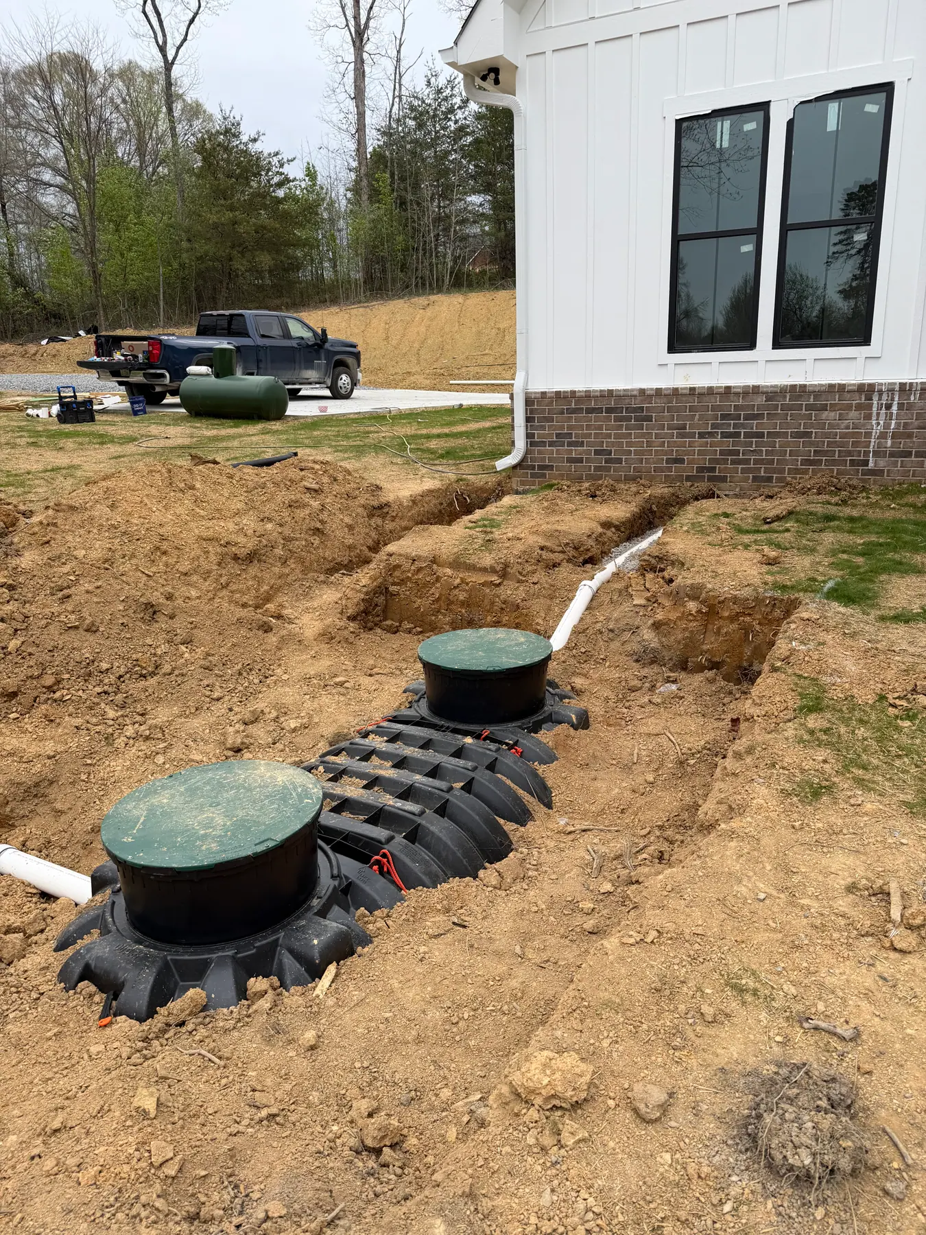 Septic tank with green access covers installed beside a house