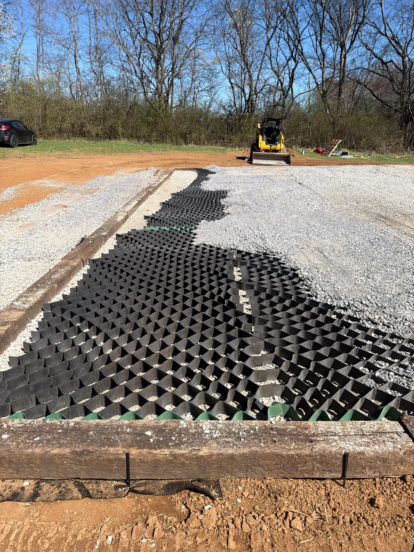 Gravel being placed into a cellular base within a framed pad